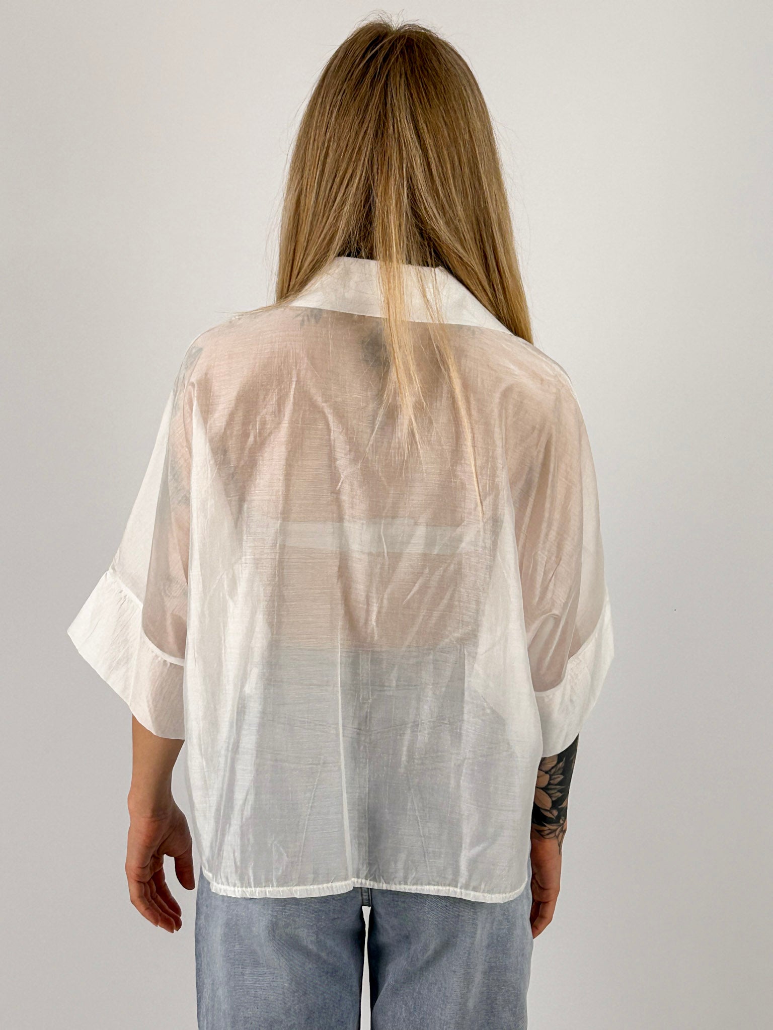 Camicia Nora da donna leggera effetto vedo-non-vedo indossata con jeans chiari. bianca vista retro