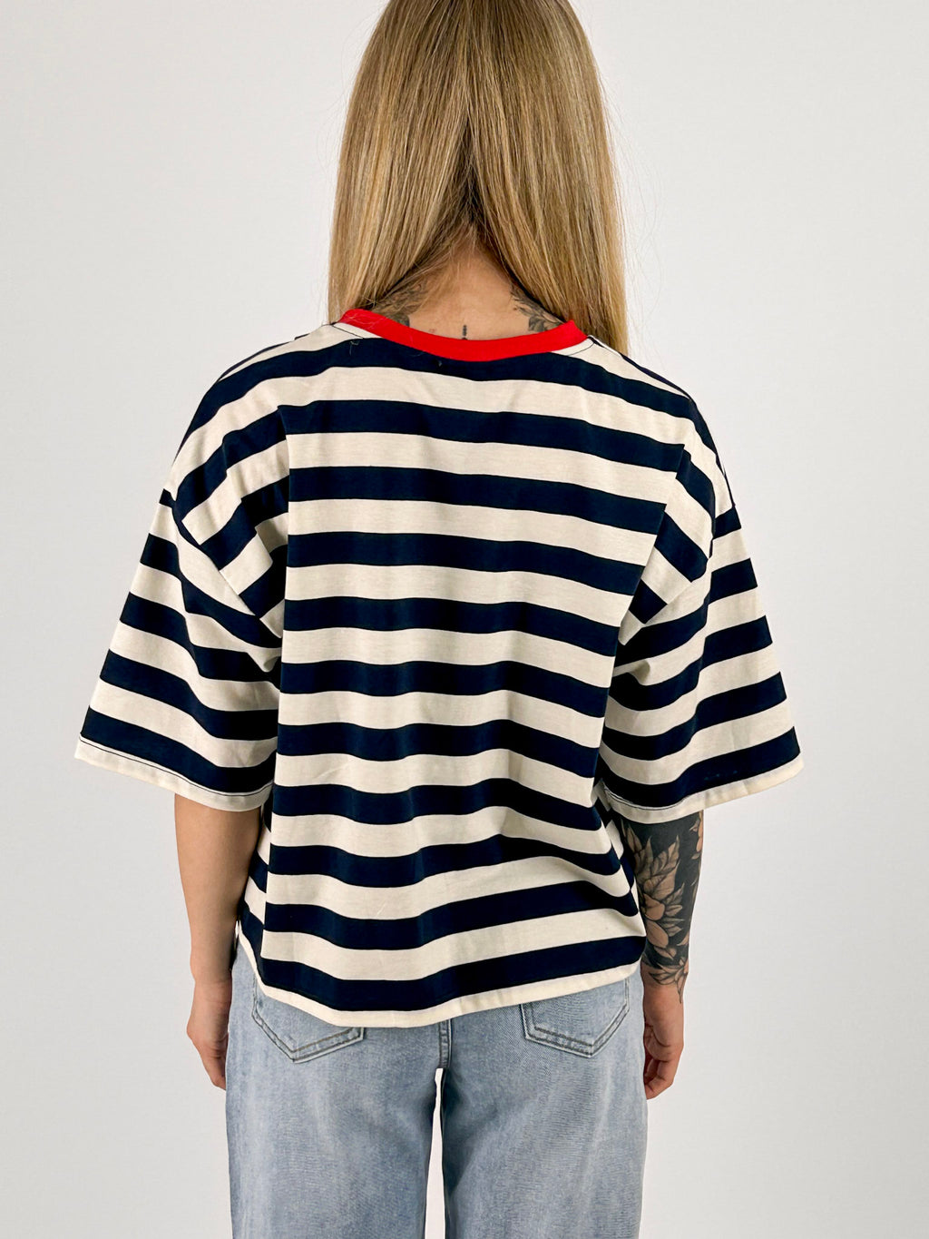 T-shirt Prosecco da donna a righe con stampa frontale indossata con jeans chiari. vista retro