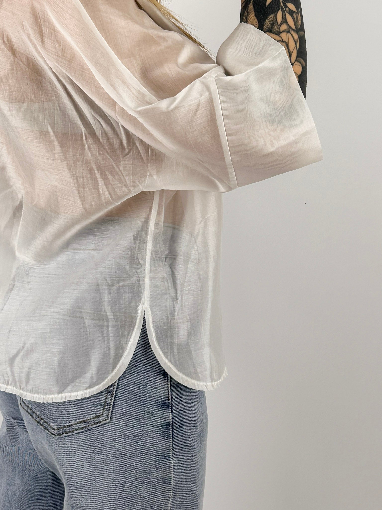 Camicia Nora da donna leggera effetto vedo-non-vedo indossata con jeans chiari. bianca dettaglio spacco