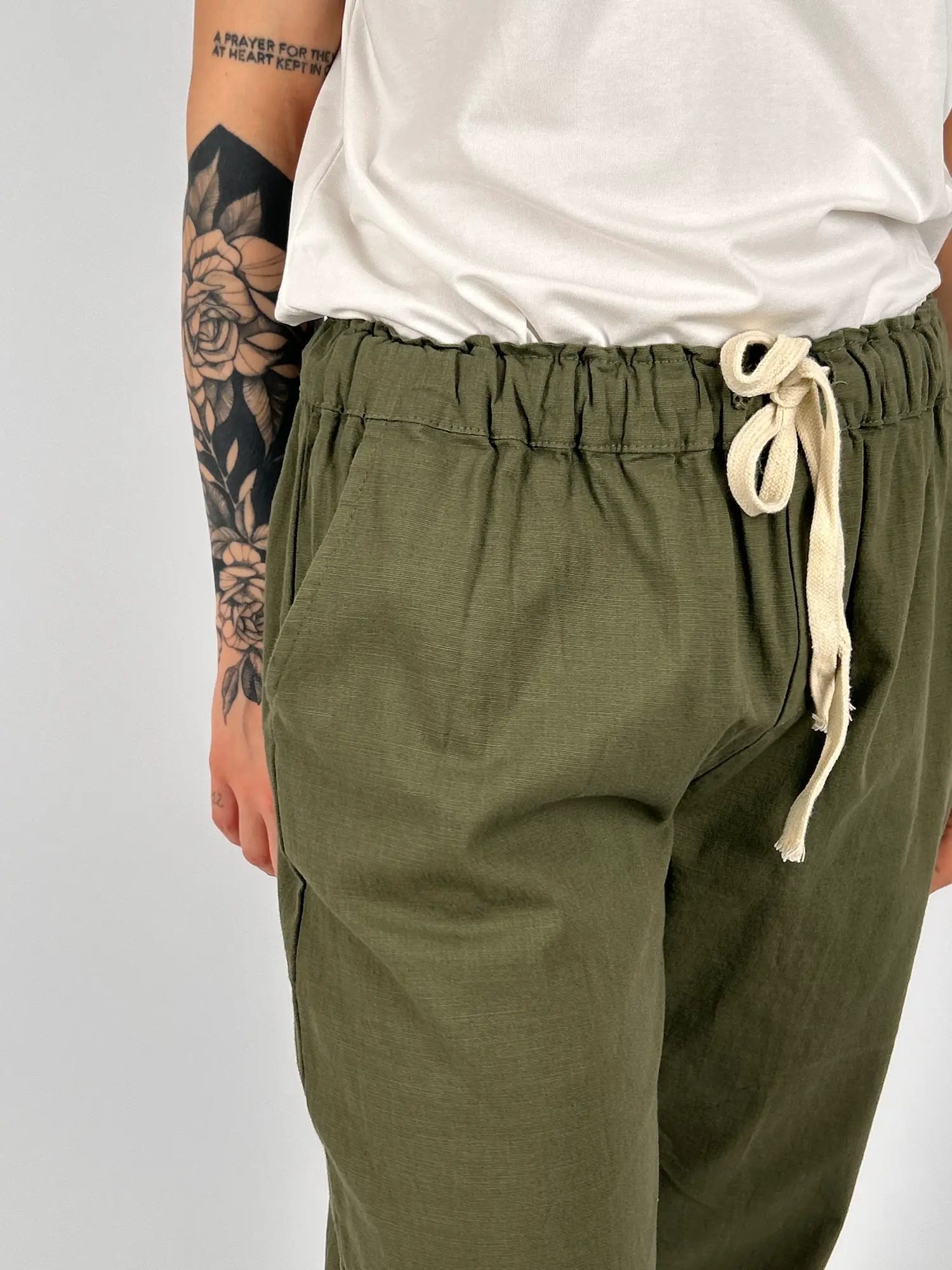 Pantalone donna verde con vita elastica e dettaglio ricamato sul fondo indossato con sabot marroni. dettaglio tasca