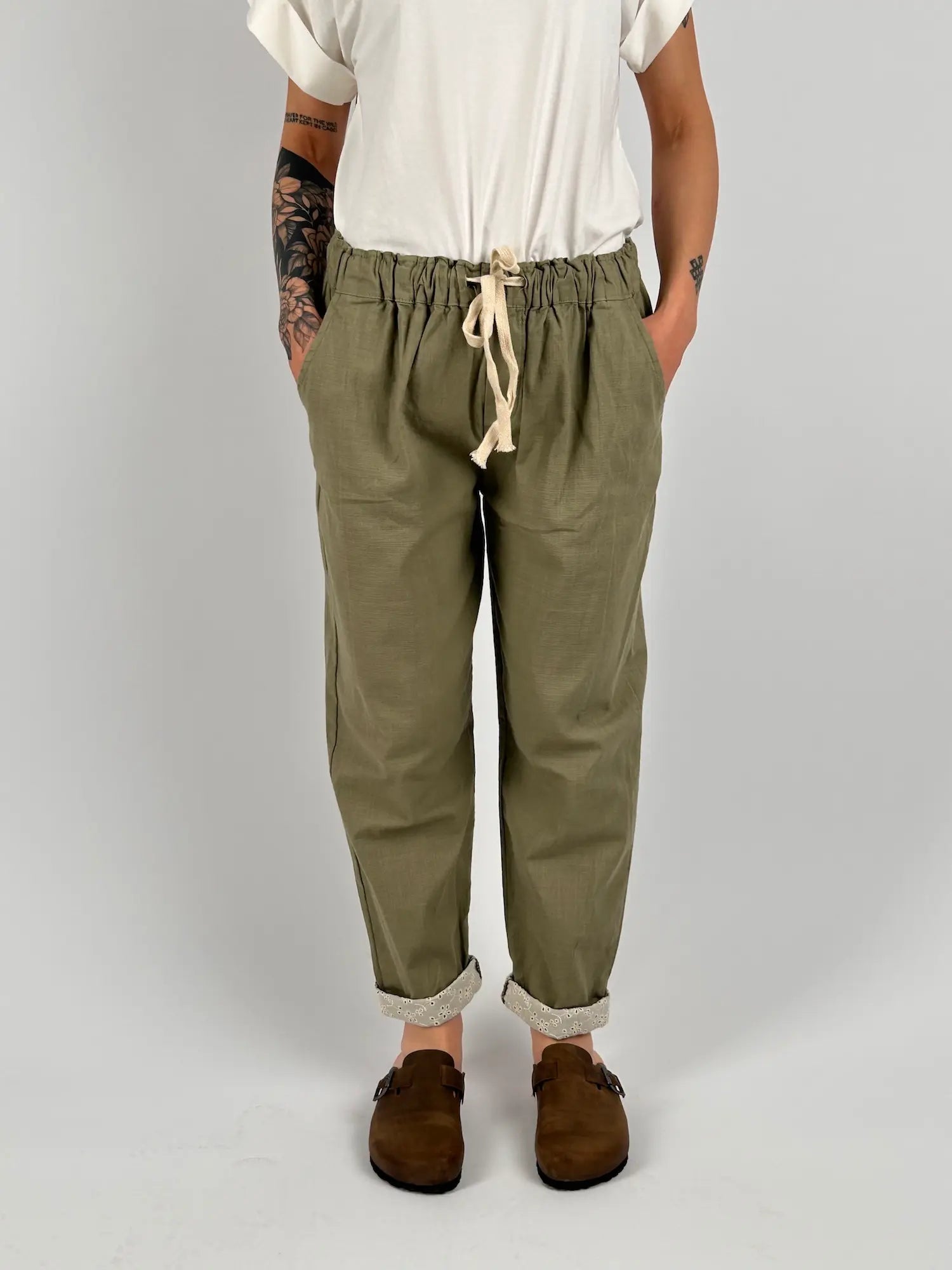 Pantalone donna verde salvia con vita elastica e dettaglio ricamato sul fondo indossato con sabot marroni