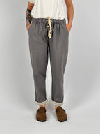 Pantalone donna grigio con vita elastica e dettaglio ricamato sul fondo indossato con sabot marroni