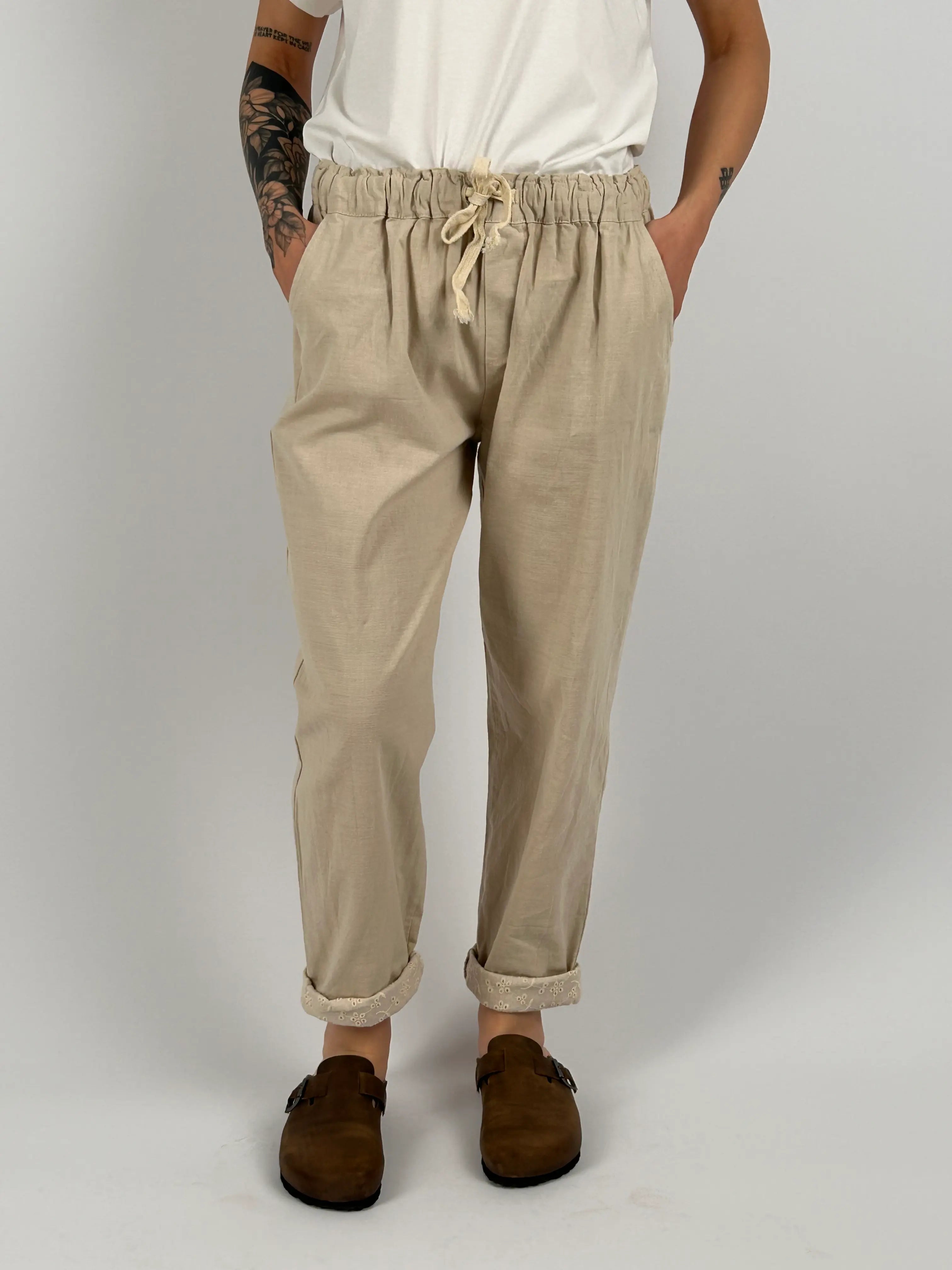 Pantalone donna panna con vita elastica e dettaglio ricamato sul fondo indossato con sabot marroni