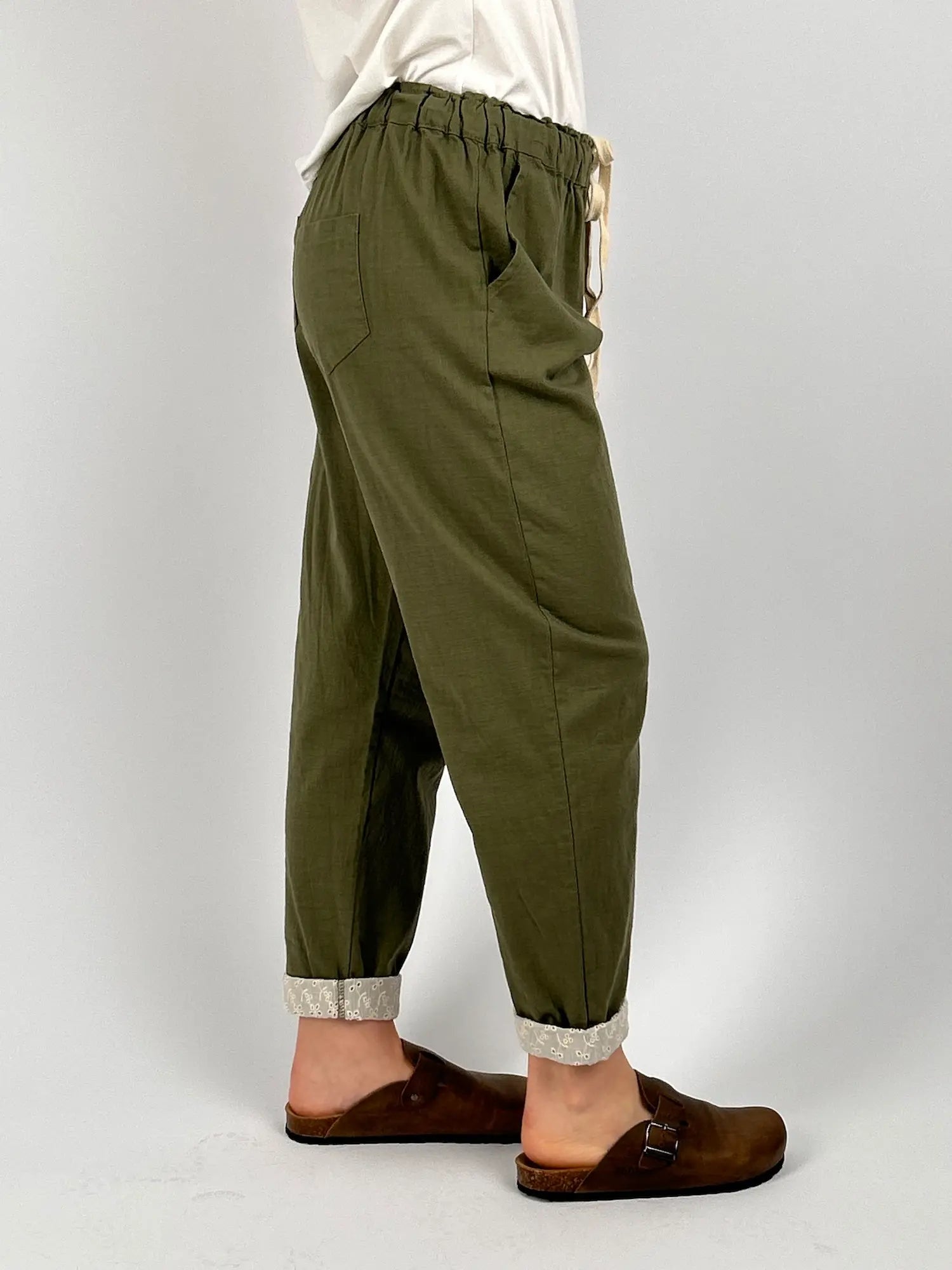 Pantalone donna verde con vita elastica e dettaglio ricamato sul fondo indossato con sabot marroni. vista laterale