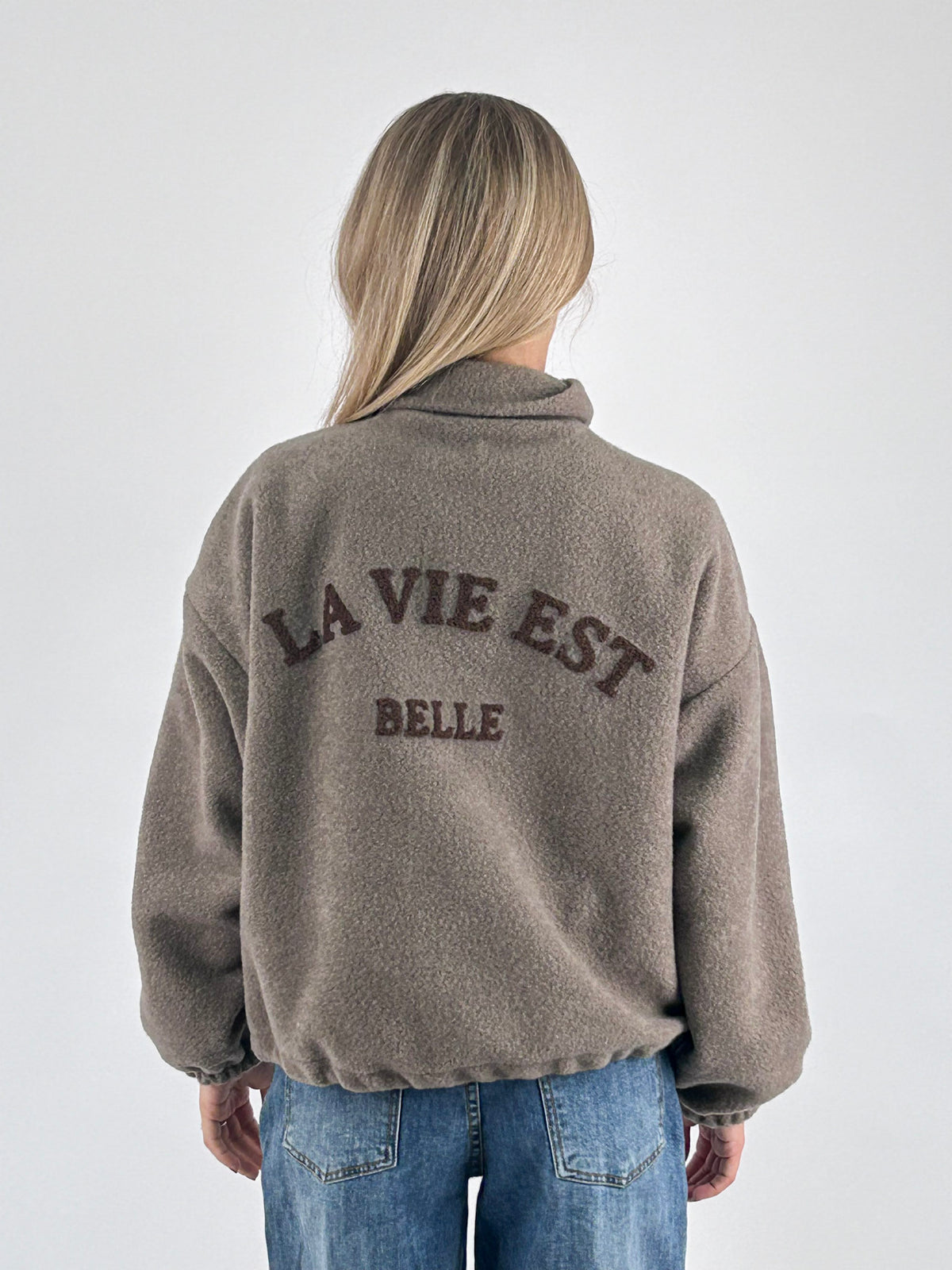 Giubbino donna con zip e collo alto con scritta La vie est belle sul retro tortora - vista retro