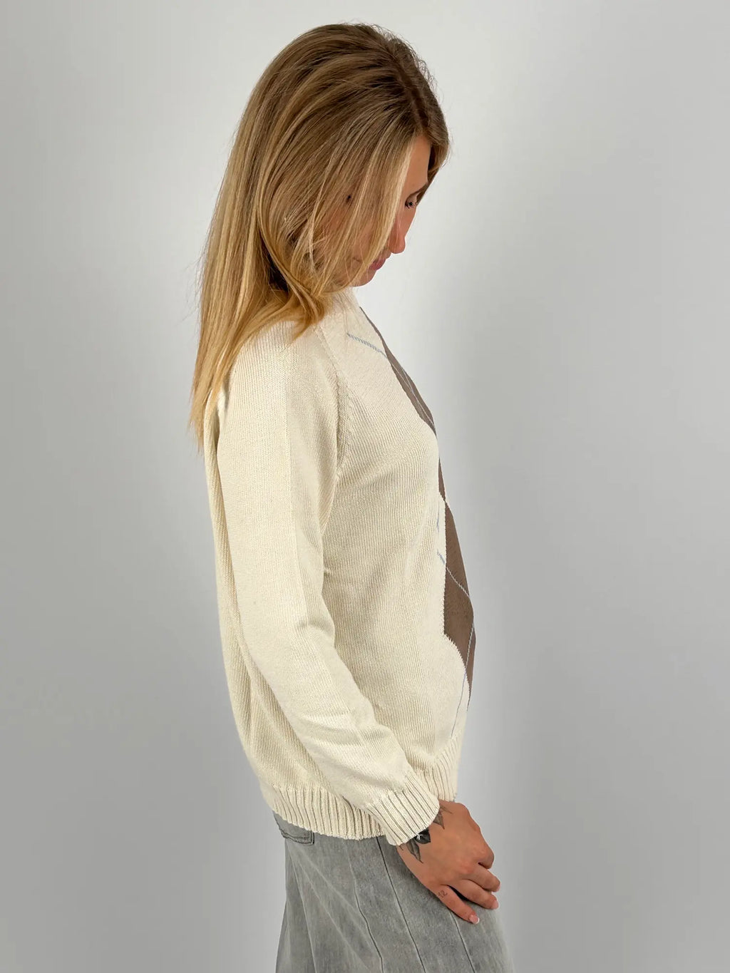 Maglia donna rosa con fantasia a rombi marroni e azzurri indossata con jeans chiari.vista laterale