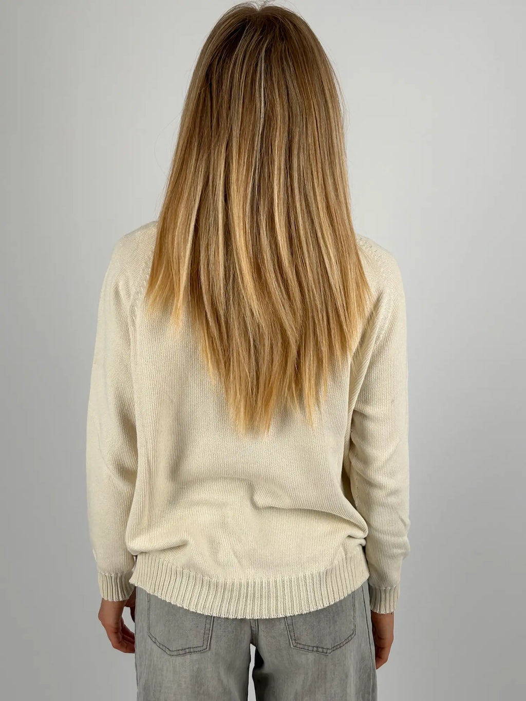 Maglia donna rosa con fantasia a rombi marroni e azzurri indossata con jeans chiari.vista retro