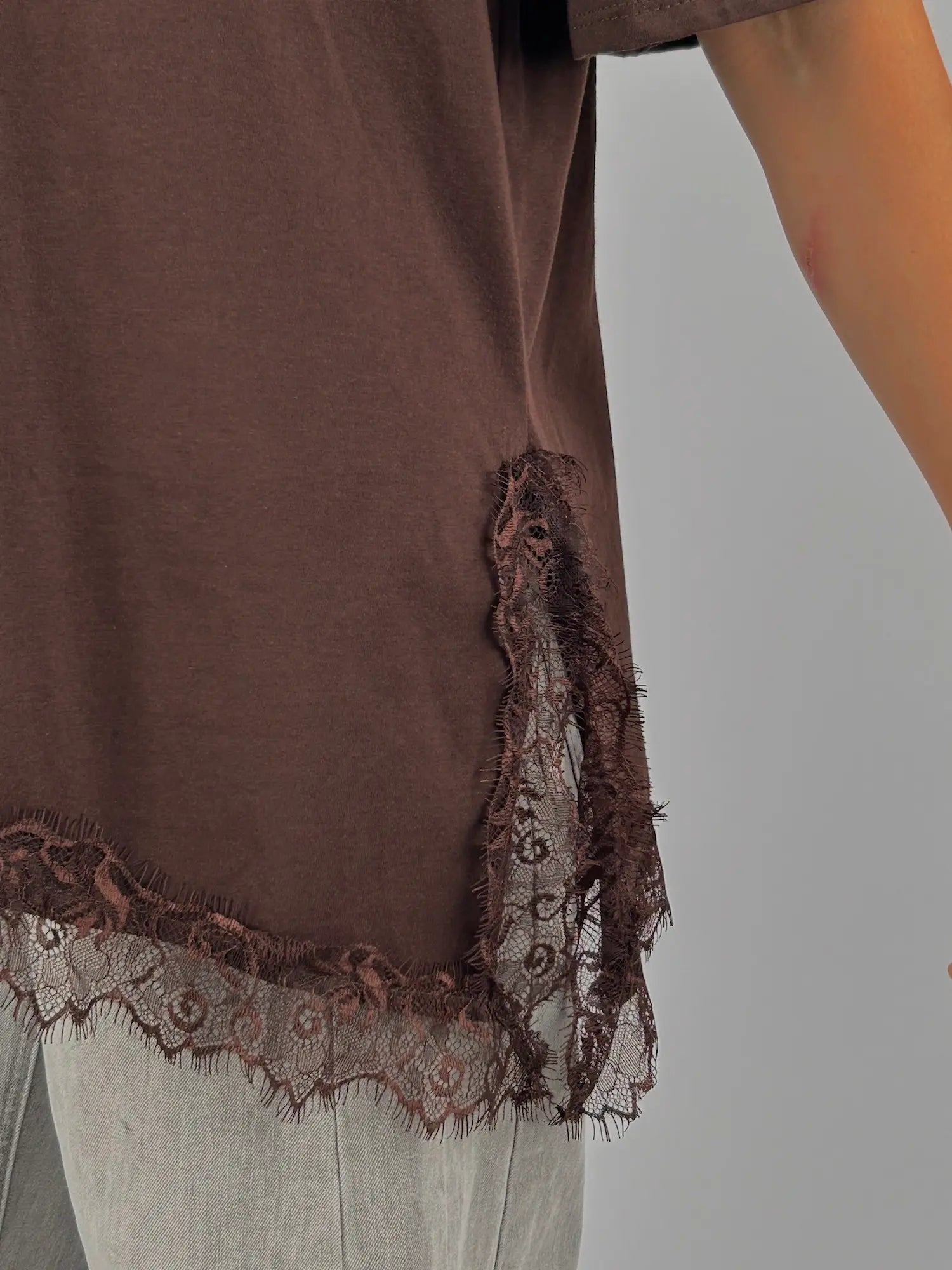 T-shirt donna marrone over con dettaglio in pizzo sul fondo indossata con jeans chiari. vista dettaglio