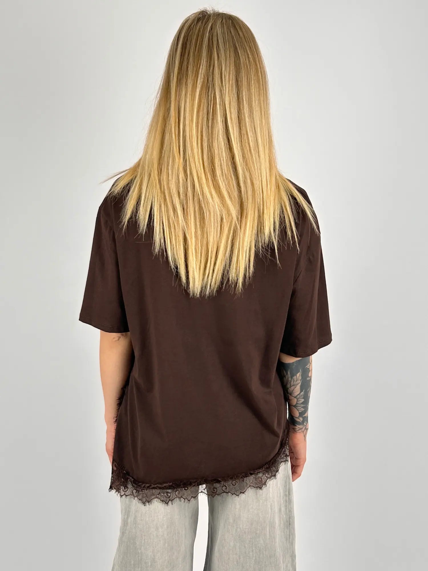 T-shirt donna marrone over con dettaglio in pizzo sul fondo indossata con jeans chiari. vista retro